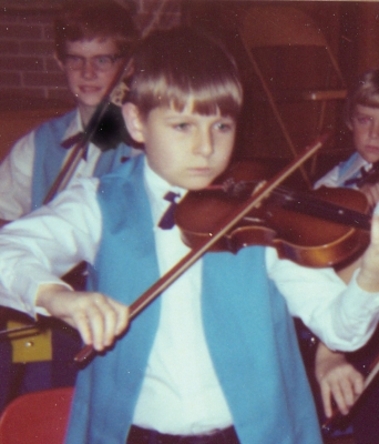 Young Randall Franks playing violin in orchestra